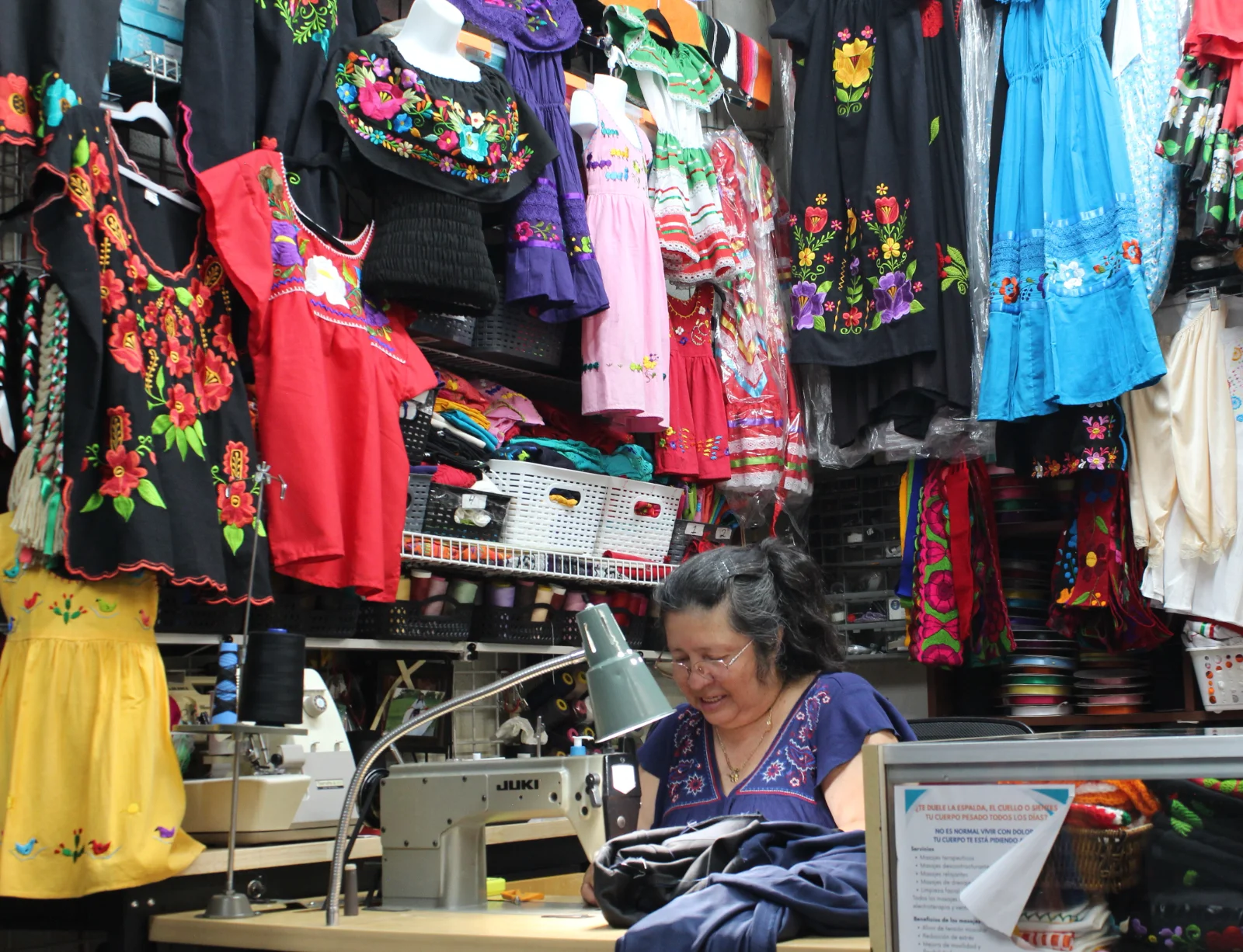 El taller de costura de La Placita, con vestidos bordados colgados sobre la máquina